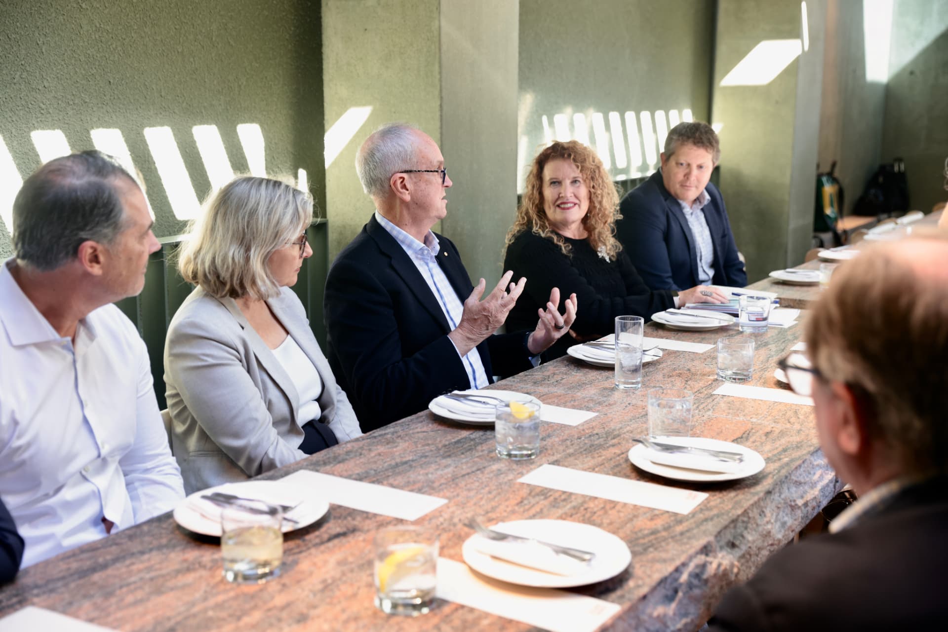 A participant gesturing while making a point across the table