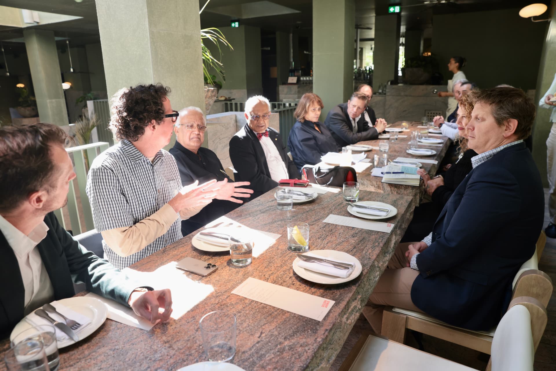 Sunlight across the long stone table as the Brisbane conversation begins